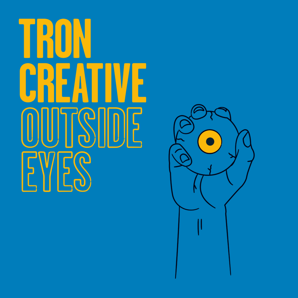 Outside Eyes promotional visual. Text reading Tron Creative Outside Eyes with a hand holding an eyeball with a yellow iris against a blue background.